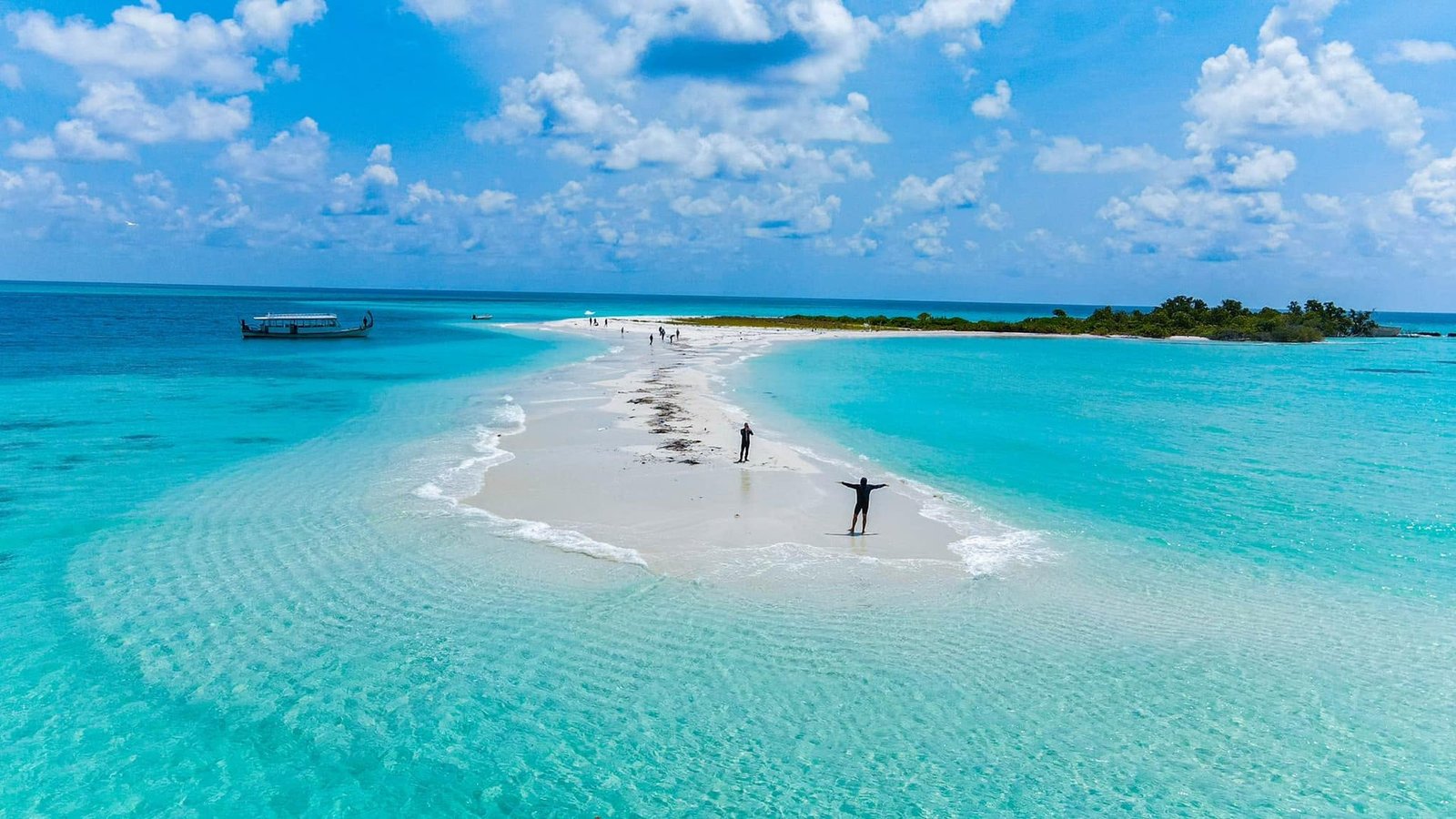 Guests walking a white sandbank in turquoise water